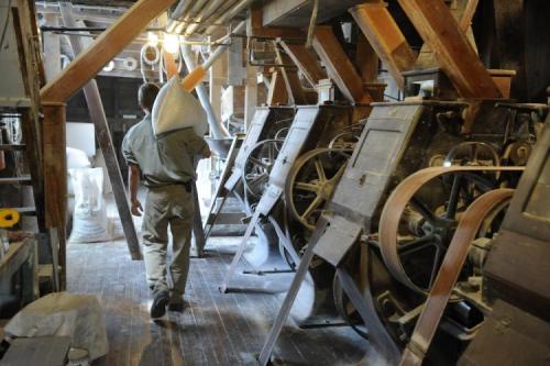 Photo of worker with sack over shoulder walking past machinery